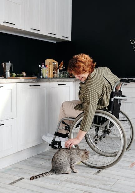 Woman Sitting on Wheelchair While Touching Her Cat