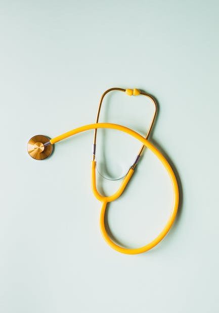 Top view of yellow medical stethoscope placed on white surface during coronavirus pandemic