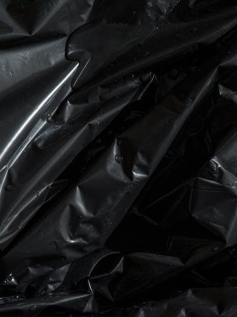 From above of smooth surface of black crumpled plastic bag as abstract background