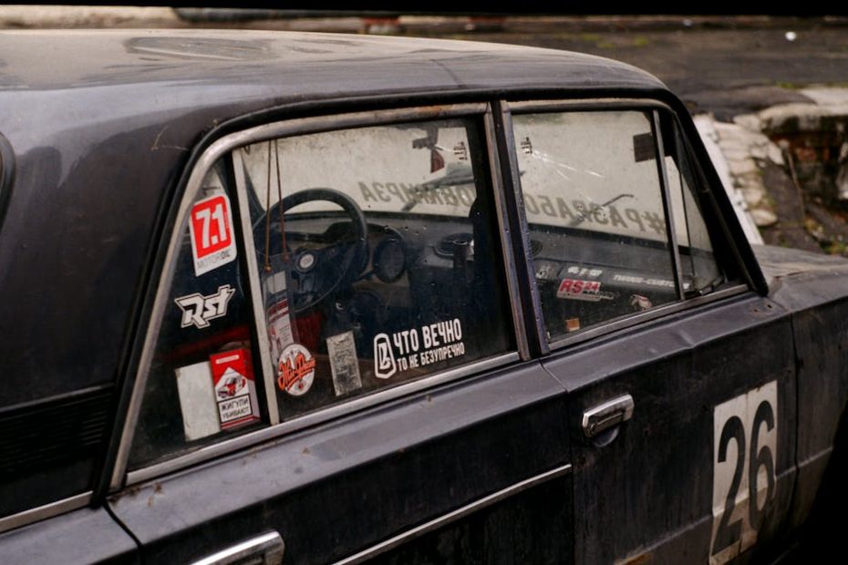 Retro automobile with colorful stickers with numbers and titles on street in town